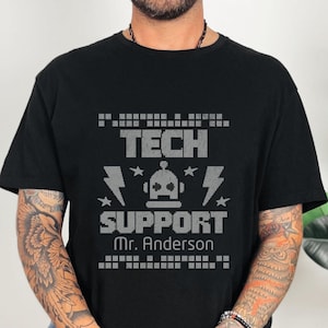 May include: Black t-shirt with a pixelated design that says "Tech Support" with a robot graphic and the text "Mr. Anderson".