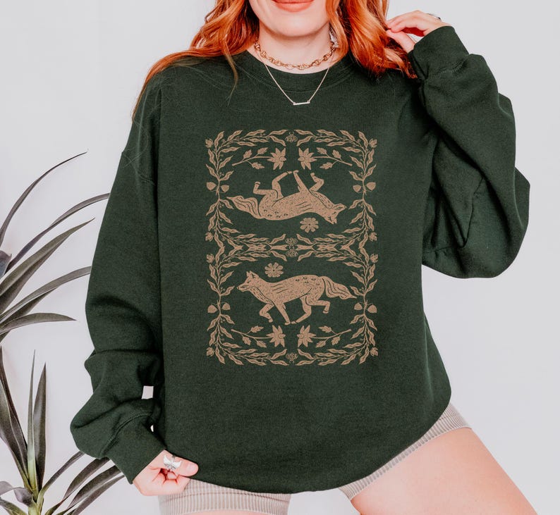 May include: A dark green sweatshirt with a graphic print of two foxes in a floral design. The foxes are in a light brown color.