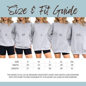May include: A size and fit guide for a gray sweatshirt. The guide shows five models wearing the sweatshirt in sizes S, M, L, XL, and 2XL. The chart below provides measurements for width and length in inches. The text at the top says "Size & Fit Guide".
