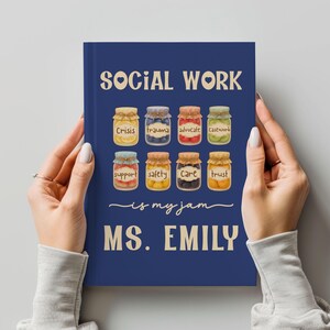 May include: A navy blue journal with the text "SOCIAL WORK is my jam MS. EMILY." The cover features illustrations of eight jars labeled "Crisis," "Trauma," "Advocate," "Casework," "Support," "Safety," "Care," and "Trust."