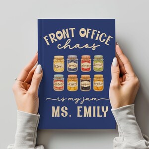 May include: A navy blue notebook with the text "FRONT OFFICE chaos is my jam MS. EMILY." The cover features illustrations of eight jars with labels like "learn," "fairness," and "diversity."