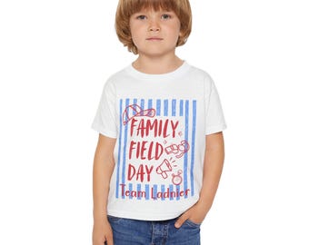 May include: White t-shirt with blue vertical stripes and red text that reads "FAMILY FIELD DAY Team Ladnier". The shirt features illustrations of a baseball cap, whistle, megaphone, and stopwatch.