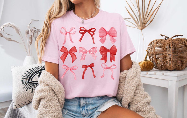 May include: A pink t-shirt with a graphic of nine red and pink bows. The bows are arranged in three rows of three.