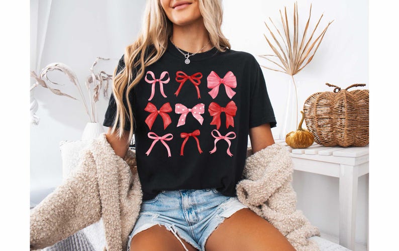 May include: A black t-shirt with a graphic of pink and red bows. The bows are arranged in a grid pattern.