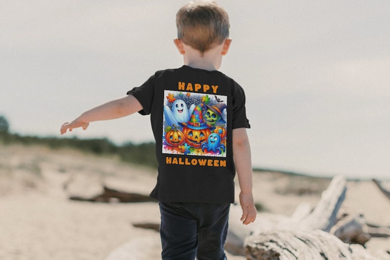 May include: Black t-shirt featuring a colorful Halloween graphic with a ghost, pumpkin, skull, and other characters. The words "HAPPY HALLOWEEN" are printed in orange above and below the graphic. The shirt is worn by a child.