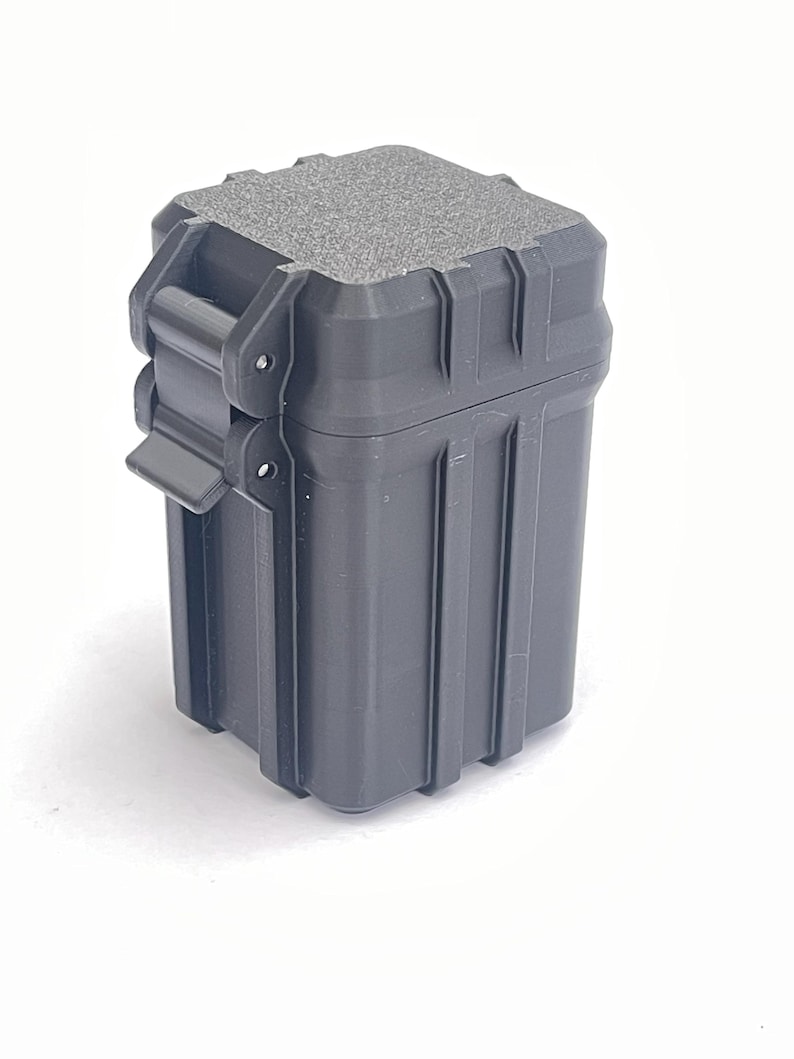 May include: A black plastic storage box with a textured lid and a latch. The box has a rectangular shape and is about 3 inches tall.