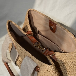 May include: A handmade crochet raffia purse bag with beige canvas lining, brown leather strap details, inner pocket, and natural boho summer style. A lightweight handmade raffia handbag for casual, beach, and everyday outfits.