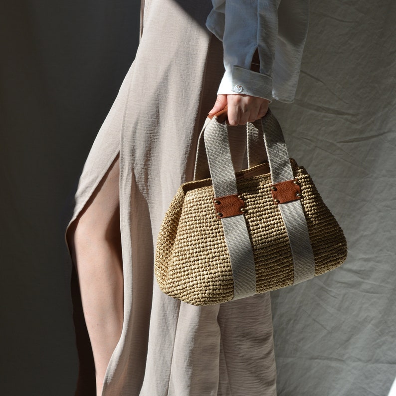 Crochet raffia purse bag handcrafted from premium raffia, featuring leather details and cotton handles, perfect for linen looks, coastal style, and quiet luxury summer wardrobes.