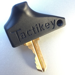 Könnte beinhalten: Ein schwarzer Schlüssel mit einem Tactileyo-Logo und einer goldenen Schlüsselklinge.