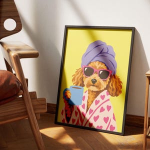 Op de afbeelding: Een ingelijste kunstdruk met een bruine poedel die een paarse handdoek op het hoofd, een roze zonnebril en een lichtroze badjas met een rood hartjespatroon draagt. De poedel houdt een lichtblauwe mok vast tegen een effen gele achtergrond.