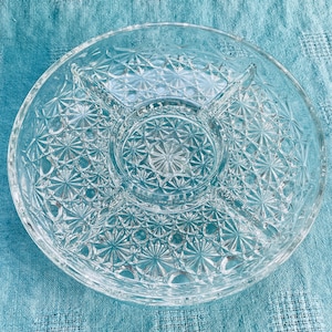 May include: A clear glass serving dish with four sections and a centre dip. The dish has a starburst pattern.
