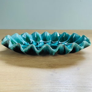 May include: A large, teal-coloured ceramic serving dish with a wavy, scalloped edge. The dish has a mottled, marbled effect.