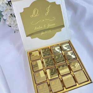 May include: A gold-colored box of chocolates with a personalized design. The box lid features the initials "D J", the names "Dalia & Jeison", and the date "Jun 07 25". Each chocolate square is also gold-colored and engraved with the same design.