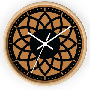 Pode incluir: Um relógio de parede com padrão marrom e preto com ponteiros brancos. O mostrador do relógio apresenta um design de mandala preto sobre fundo marrom.