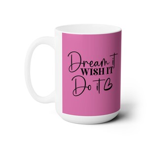 May include: White ceramic mug with a pink background and black text that reads "Dream it Wish it Do it ".