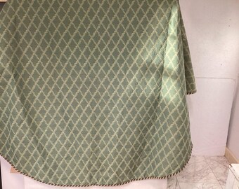 Mantel redondo hecho a mano de color verde con ribete trenzado en rojo, blanco y verde, diámetro 89 cm.