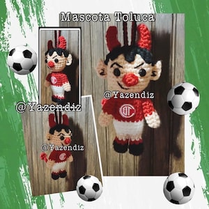May include: Crocheted mascot of Toluca, featuring a red and white outfit with a devilish design. The mascot has red horns, a red nose, and a smiling face. The image includes soccer balls and the text "Mascota Toluca" and "@Yazendiz".