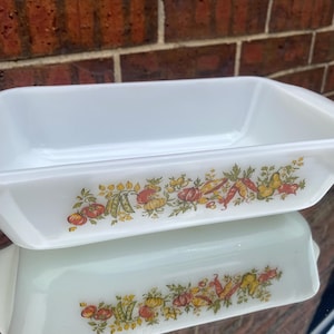 May include: White rectangular baking dish with a colorful vegetable design. The dish features illustrations of tomatoes, peas, and other vegetables. The dish is made of glass and is likely vintage.