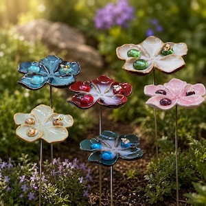 May include: A collection of six ceramic flower garden stakes, each featuring five petals and a central stem. The flowers are glazed in blue, white, red, light green, dark green, and pink, with small glass marbles and bee figurines on the petals.