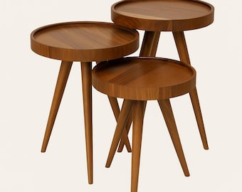 May include: Three wooden side tables of different sizes. Each table has a circular top with a raised edge and three angled legs. The tables are made of warm-toned wood, and the design is mid-century modern.