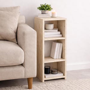 Peut inclure: Une bibliothèque beige clair à trois étagères de forme carrée. L'étagère supérieure contient une petite plante en pot, des livres et une bougie allumée. L'étagère du milieu contient des livres et un petit bol. L'étagère inférieure contient des livres et deux petits récipients.
