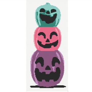May include: A stack of three smiling jack-o'-lanterns in a cross-stitch design. The pumpkins are in shades of teal, pink, and purple, with black facial features. The design is on a white background, perfect for Halloween decor.