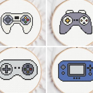 Può includere: Quattro cerchi da ricamo a punto croce con controller di videogiochi. I controller sono bianchi, grigi e blu, con dettagli neri. Ogni controller ha un design diverso, tra cui una console portatile e un gamepad classico.