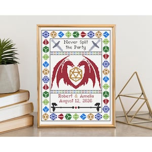 Könnte beinhalten: Gerahmte Kreuzstichkunst in einem goldenen Rahmen. Das Design zeigt einen roten Drachen mit einem goldenen Würfel, den Text "Never Split the Party" und die Namen Robert & Amelia mit dem Datum 12. August 2026. Der Rand hat geometrische Formen.