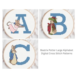 May include: Three cross-stitch patterns featuring letters A, B, and C, each within a round hoop. The letters are blue, and each is accompanied by a Beatrix Potter character: a mouse, a rabbit, and another rabbit. The text "Beatrix Potter Large Alphabet" is visible.