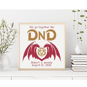 Può includere: Opera d'arte a punto croce incorniciata in oro. Il design presenta il testo "We go together like DND" in oro, ali di drago rosse e un dado D20 dorato. Sotto, si legge "Robert & Amelia August 12, 2026".