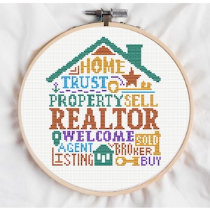 May include: A cross-stitch design in a wooden hoop features a house shape with the words "HOME, TRUST, PROPERTY, SELL, REALTOR, WELCOME, AGENT, LISTING, BROKER, BUY" in various colors. The design includes keys, a star, and a house icon.