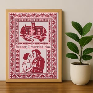 May include: A framed cross-stitch picture with a red and white design. The top section shows a building and landscape, the bottom a couple. The text "Reader, I married him." is included. The frame is light brown. The artwork is displayed on a wooden surface.