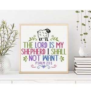 May include: A framed cross-stitch artwork with the text "THE LORD IS MY SHEPHERD I SHALL NOT WANT" in various colors. A cartoon sheep is above the text, and the scripture reference "PSALM 23:1" is below. The frame is a light wood color.