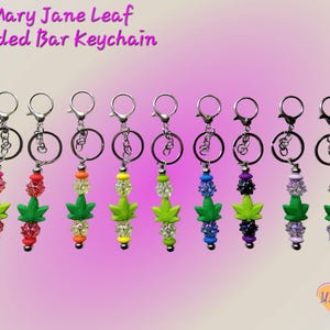 May include: A collection of beaded bar keychains with a cannabis leaf design. Each keychain features a silver-tone clasp, a ring, and a beaded bar in various colors, including pink, red, orange, yellow, green, blue, purple, and white. The text "Mary Jane Leaf Beaded Bar Keychain" is at the top.