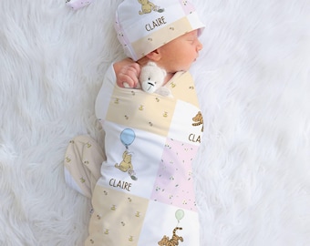 May include: A newborn baby swaddled in a Winnie the Pooh themed blanket and hat. The blanket and hat are white, pink, and yellow with Winnie the Pooh and Tigger graphics. The name "Claire" is printed on the blanket and hat.