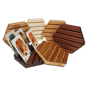 May include: Set of six hexagonal wooden card holders in various wood tones. The holders have grooves to hold cards upright. One holder has three cards in it.