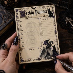 Può includere: Un blocco note settimanale rettangolare con sfondo color crema e bordi floreali viola. L'intestazione recita Weekly Planner. Presenta un gatto nero, una luna crescente, un pipistrello, un drago e una strega in piedi vicino a un castello.