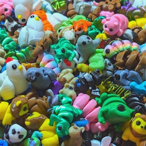 May include: A collection of colorful, small, 3D printed figurines. The figurines are made in a variety of shapes and sizes, including animals, plants, and abstract designs. The figurines are all brightly colored and have a smooth, glossy finish.