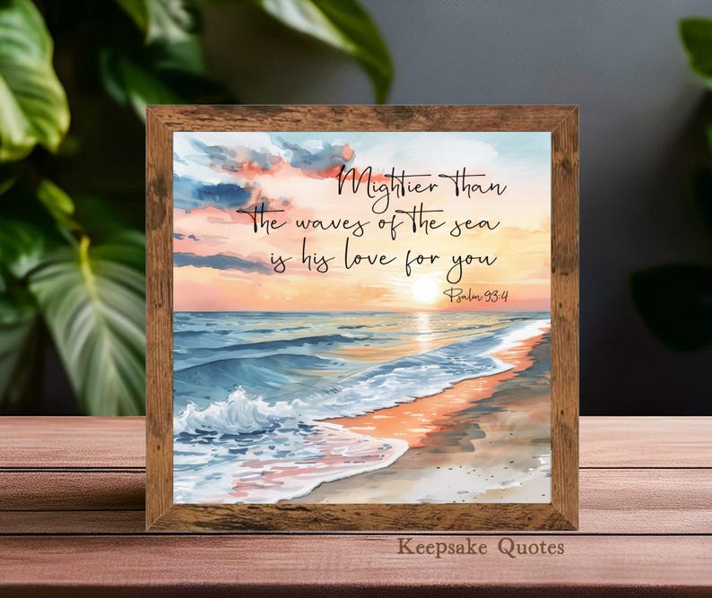 Op de afbeelding: Een ingelijste aquarelprint met een strandsc&egrave;ne bij zonsondergang. Het kunstwerk toont de quote: "Machtiger dan de golven van de zee is zijn liefde voor jou." De lijst is van hout en het kleurenpalet omvat blauw, oranje en geel.