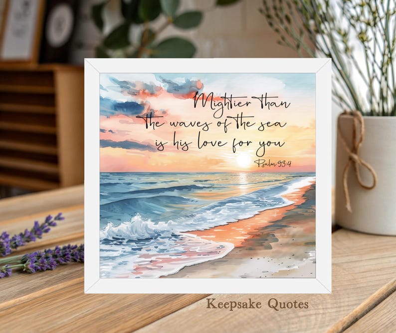 Op de afbeelding: Een ingelijste print met een aquarel strandsc&egrave;ne bij zonsondergang. Het kunstwerk bevat de tekst "Mightier than the waves of the sea is his love for you" en "Psalm 93:4". De lijst is wit en de tekst "Keepsake Quotes" staat onderaan.