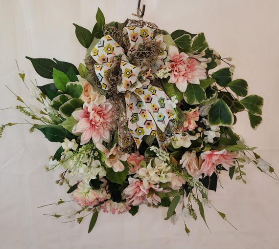 a light pink summer wreath with large bow made our of cute birdcage ribbon.