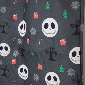 May include: A dark gray tote bag featuring a repeating pattern of Jack Skellington faces, Christmas trees, snowflakes, candy canes, and wrapped gifts. The bag has a gray handle and is made of a durable fabric.