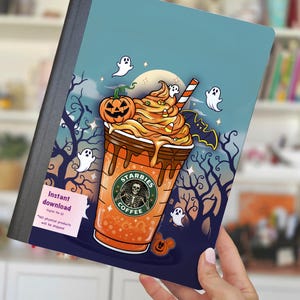 May include: A notebook with a Halloween-themed design. The cover features a cartoon coffee cup with a pumpkin, ghosts, and the text "Starbies Coffee". The background is a dark blue with trees and a full moon. The notebook is held by a hand.