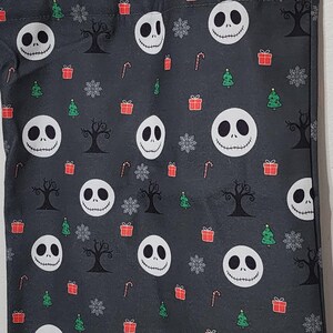 May include: A gray tote bag featuring a pattern of Jack Skellington faces, Christmas trees, snowflakes, gift boxes, and bare trees. The bag has gray handles and is likely made of fabric.