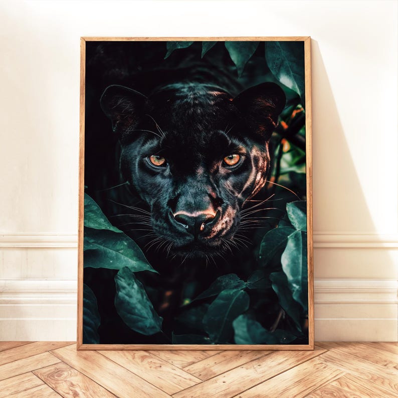 May include: A framed print featuring a black panther with piercing yellow eyes, partially obscured by lush green foliage. The panther's dark fur contrasts with the vibrant leaves, creating a dramatic and captivating image. The artwork is set in a wooden frame.