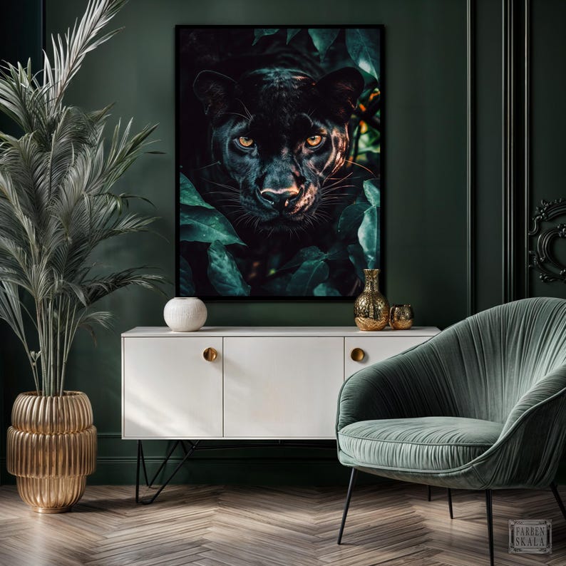 May include: A framed art print featuring a black panther's face peering out from lush green foliage. The artwork is displayed above a white cabinet with gold hardware, complemented by a gold vase and a green velvet armchair. The room has dark green walls.
