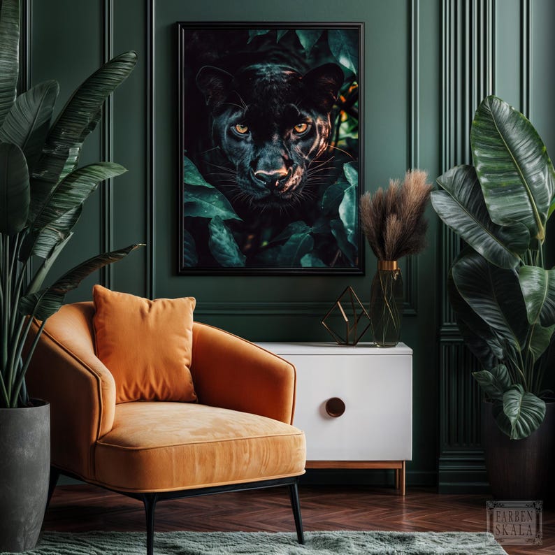 May include: A framed art print featuring a black panther peering out from lush green foliage. The panther's yellow eyes are visible. The artwork hangs above an orange armchair and a white cabinet with a wooden handle. The room has dark green walls.