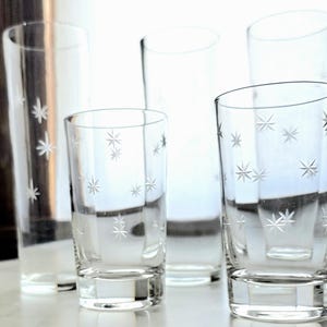 May include: A white ceramic mug with a black handle and the text "But First, Coffee" in a black, bold font. The mug is on a white surface.