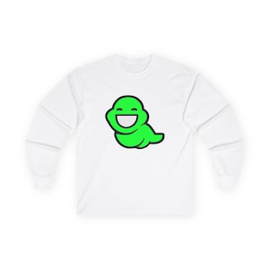 May include: White long-sleeve shirt featuring a smiling, green cartoon character. The graphic is a simple design with a black outline. The shirt is made of a soft, comfortable material.