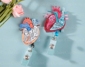 May include: Two anatomical heart-shaped badge holders with detailed illustrations of the human heart. The left heart is red and blue, the right heart is orange and yellow. Both have a black lanyard and a clear plastic badge clip.
